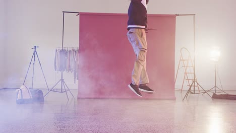 happy biracial male dancer dancing alone in dance studio, slow motion