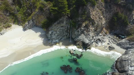 Majestuosa-Cascada-Entre-Acantilados-En-Una-Playa-Aislada-En-Big-Sur,-California---Pacific-Coast-Highway-1