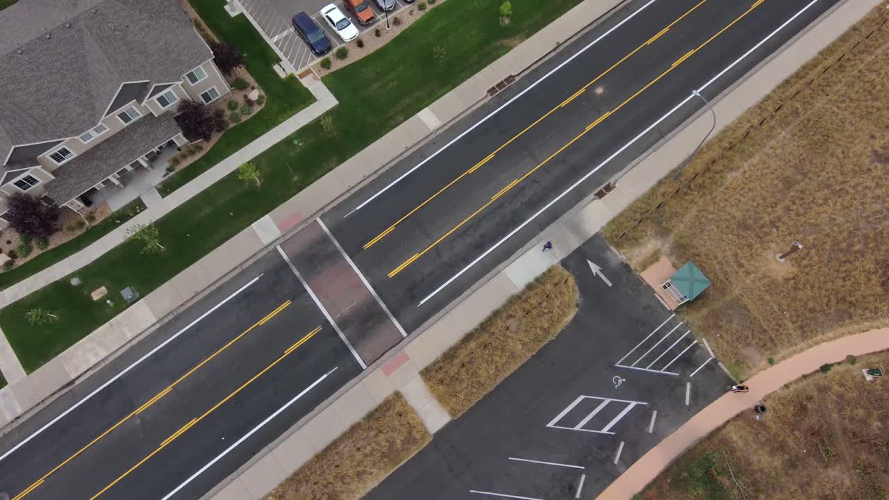 공원 근처에서 개를 산책시키는 한 남자에게 높은 드론 샷이 떨어지고 확대됩니다.