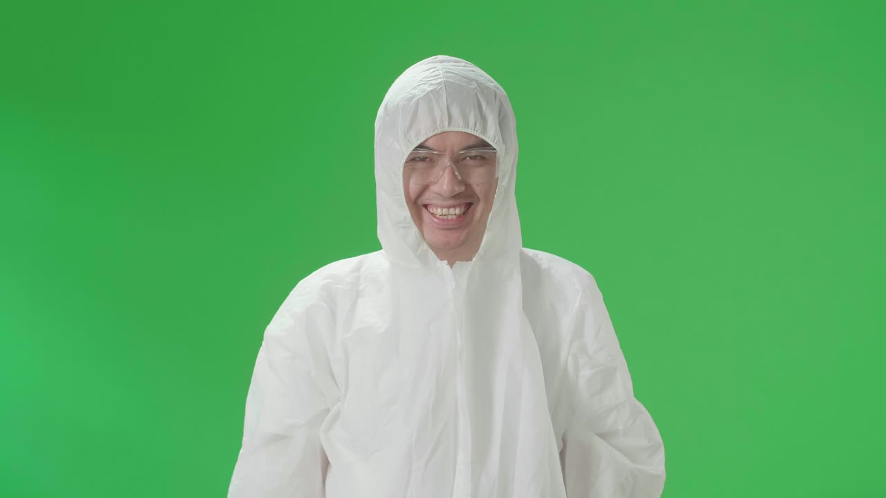 Homme asiatique portant un uniforme d'équipement de protection individuelle (EPI) et hochant la tête positivement devant la caméra dans un studio sur fond vert