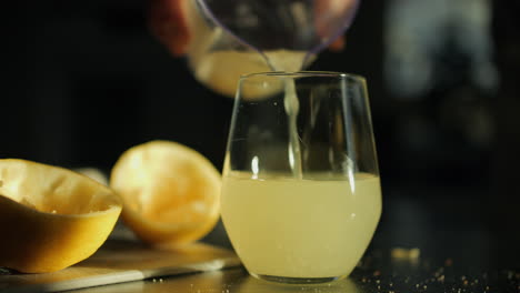 pouring freshly squeezed lemon juice into glass, natural morning light cames in, close-up