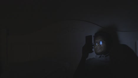 person using smartphone in bed at night