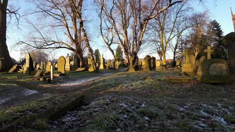 fpv flying around headstones in snowy autumn sunrise golden hour churchyard cemetery