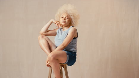 studio portrait shot of casually dressed body positive albino woman sitting on stool