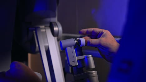 Managing the handles of futuristic surgical robot. Male doctor in blue uniform operates the high precise technological equipment Da Vinci.