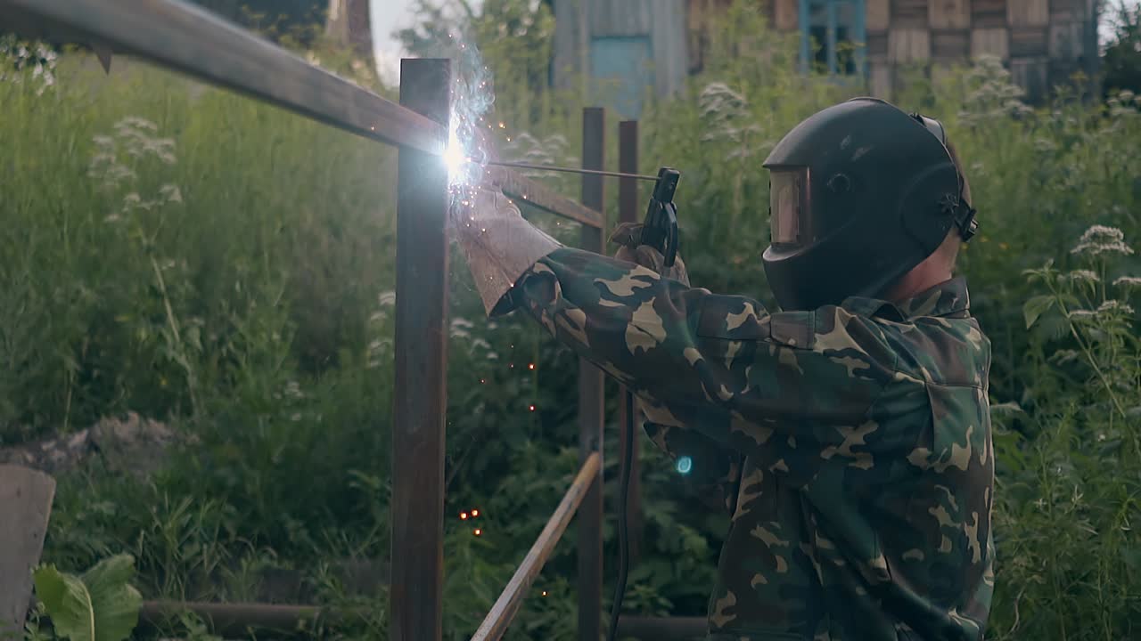 vista lateral en cámara lenta trabajador soldando valla de metal en la casa