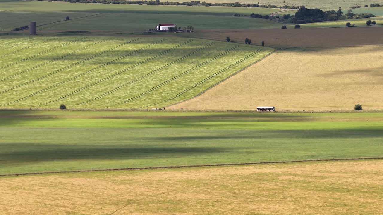 Cloud shadows following tourist coach travelling on rural road in Wiltshire farming countryside