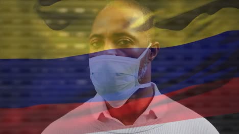 Animation-of-flag-of-colombia-waving-over-man-wearing-face-mask-during-covid-19-pandemic