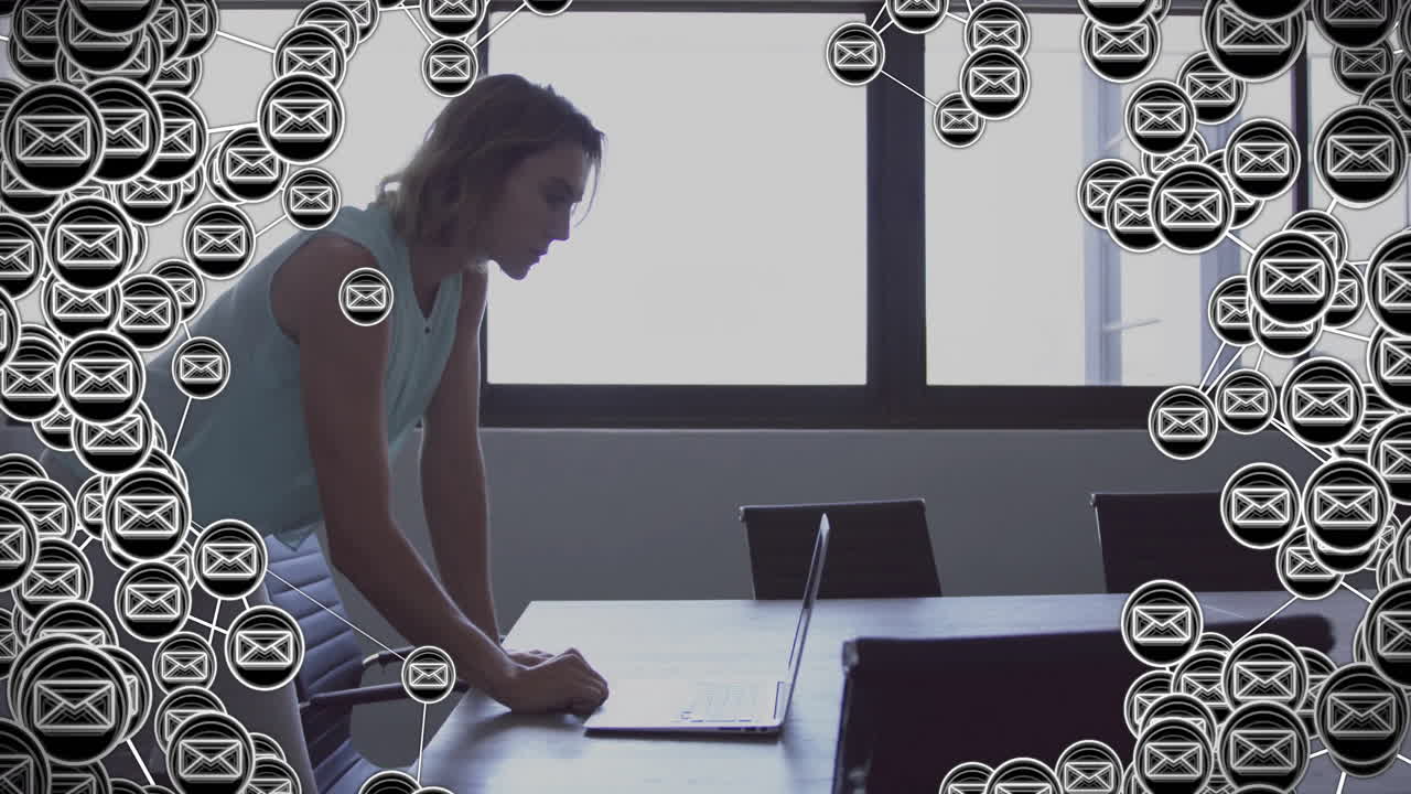 animación de iconos de sobres sobre mujer de negocios caucásica usando portátil en la oficina