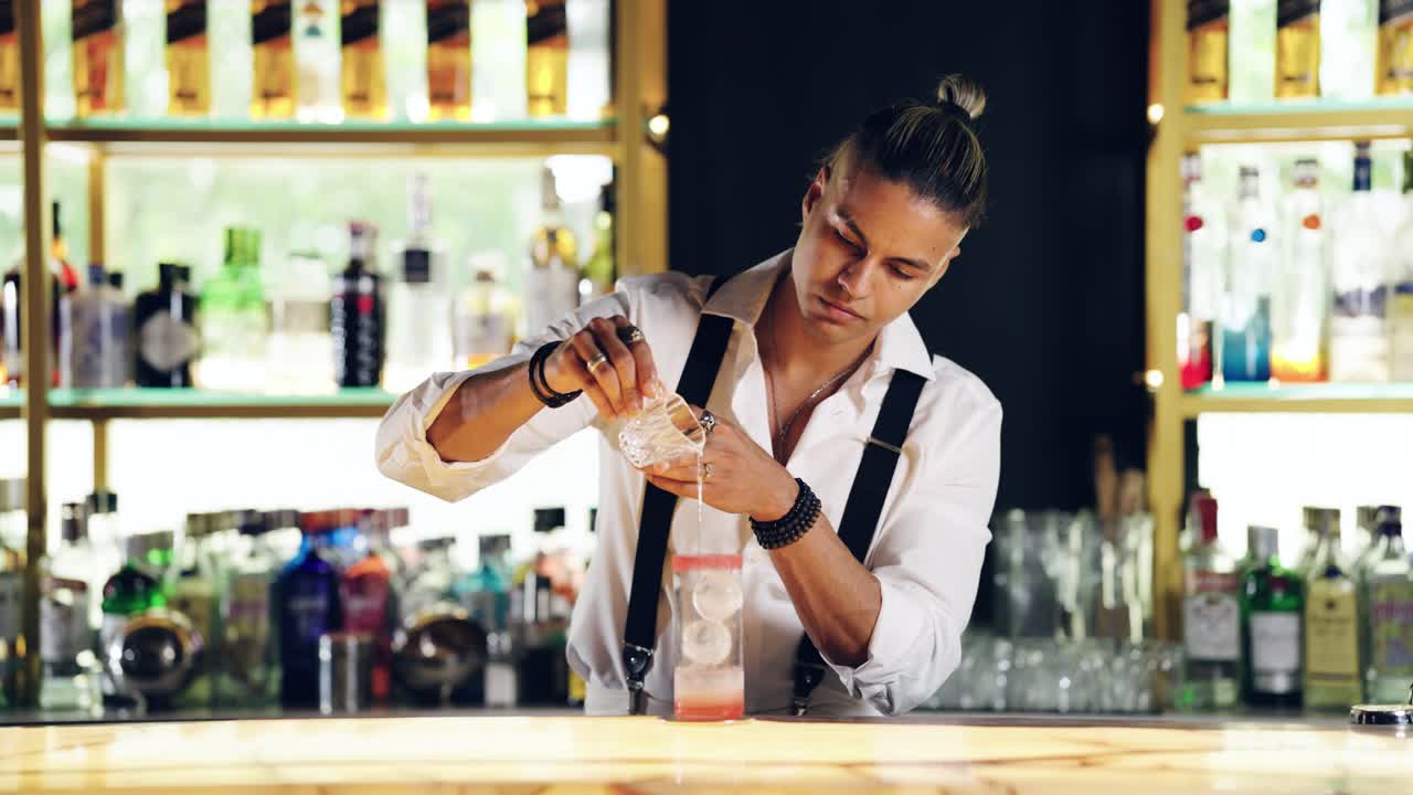 Barman profesional sirviendo una bebida en un vaso con hielo