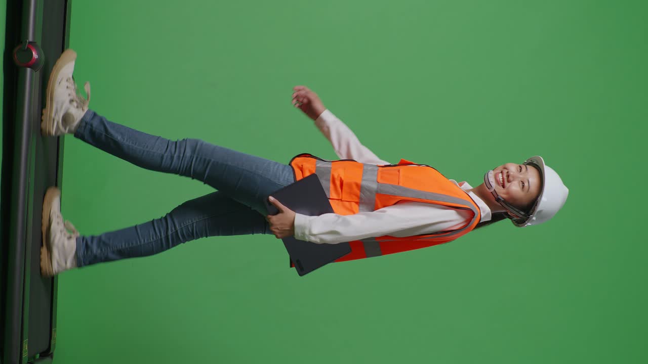 녹색 스크린 배경 스튜디오에서 는 동안 태블릿을 들고 있는 안전 헬을 입은 아시아 여성 엔지니어의 전체 몸의 측면 시각