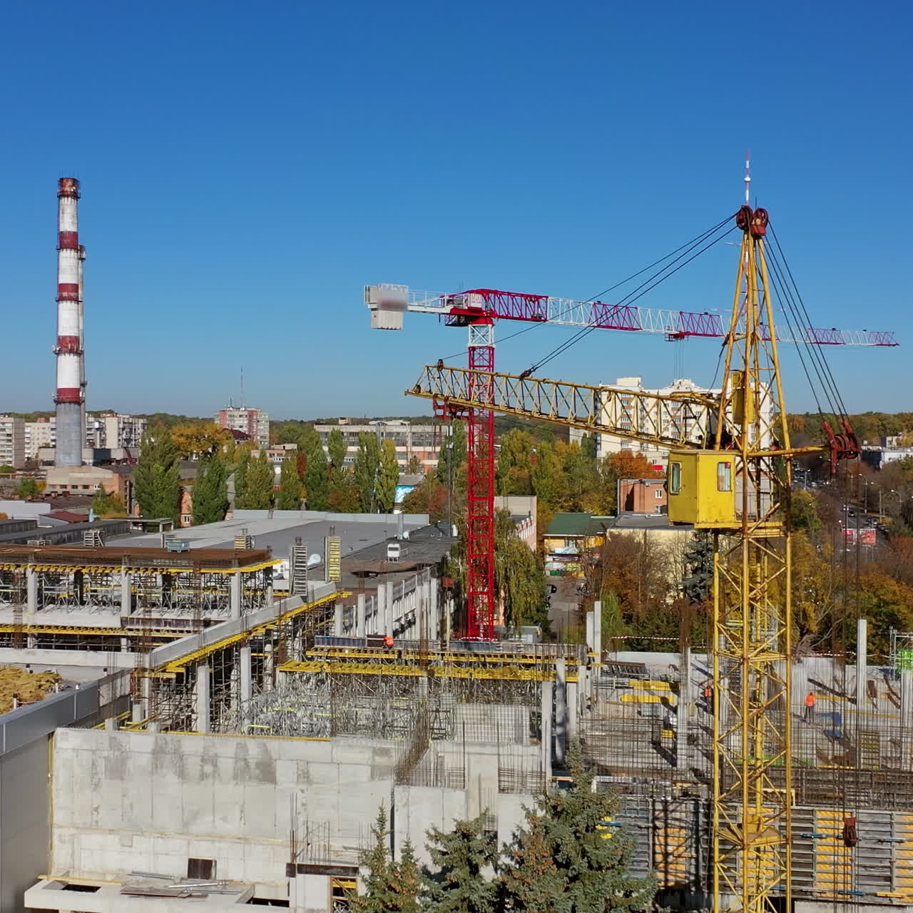 Construction of a new shopping center. Urban background and two cranes on construction site. Video shooting with drone.