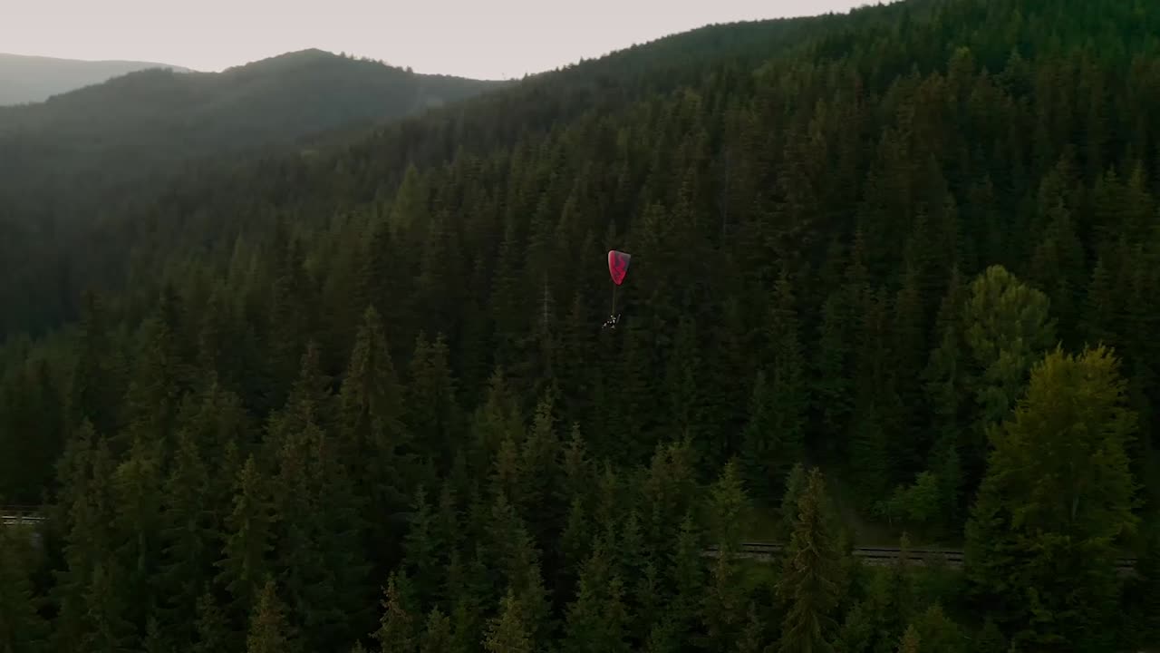 Following a paraglider with a drone flying over a beautiful old viaduct. Chmarocsky viaduct in Low Tatras, Slovakia, Europe. Paraglider is flying extremely close to the bridge. Filmed on summer sunset