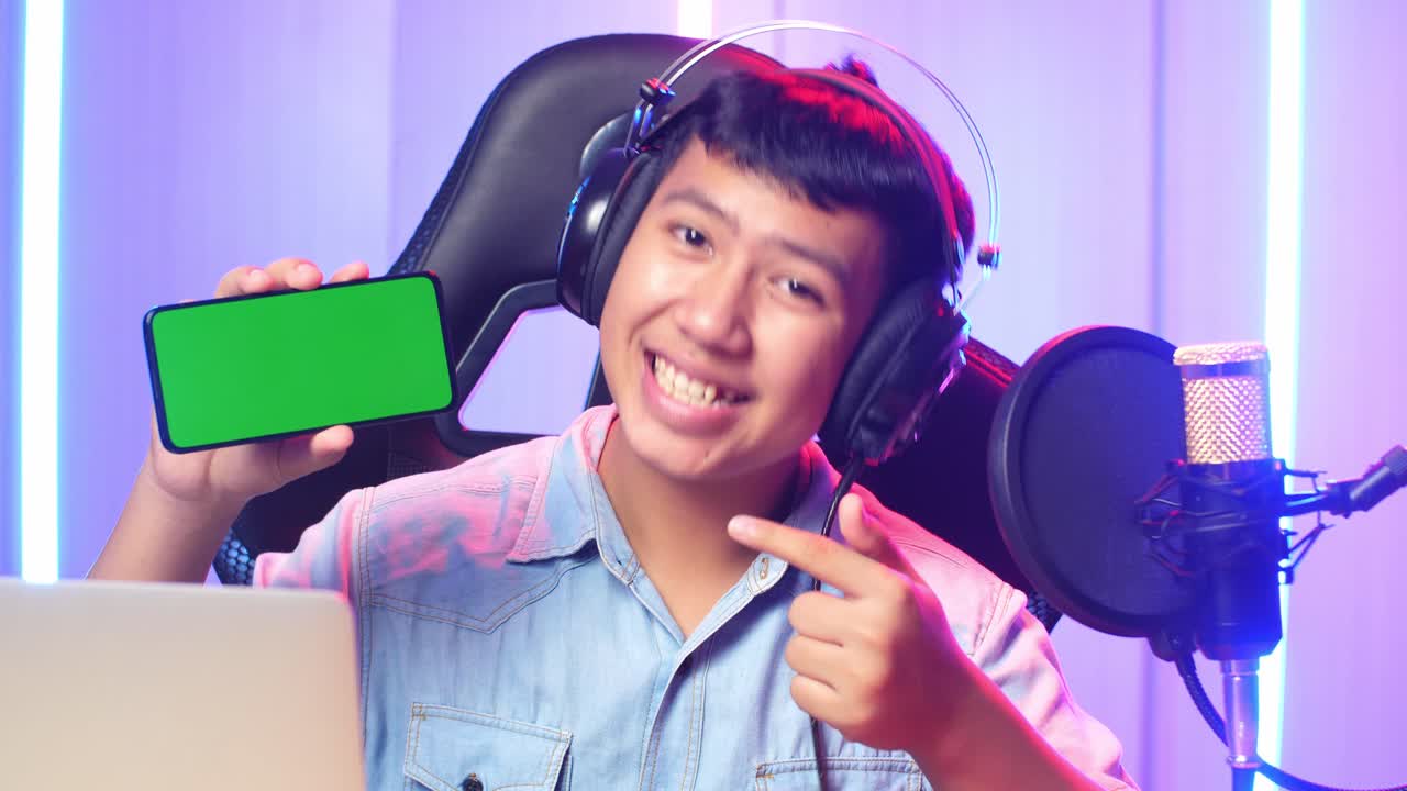 Asian Kid Boy Holding Mobile Phone With Mock Up Green Screen While Live Stream