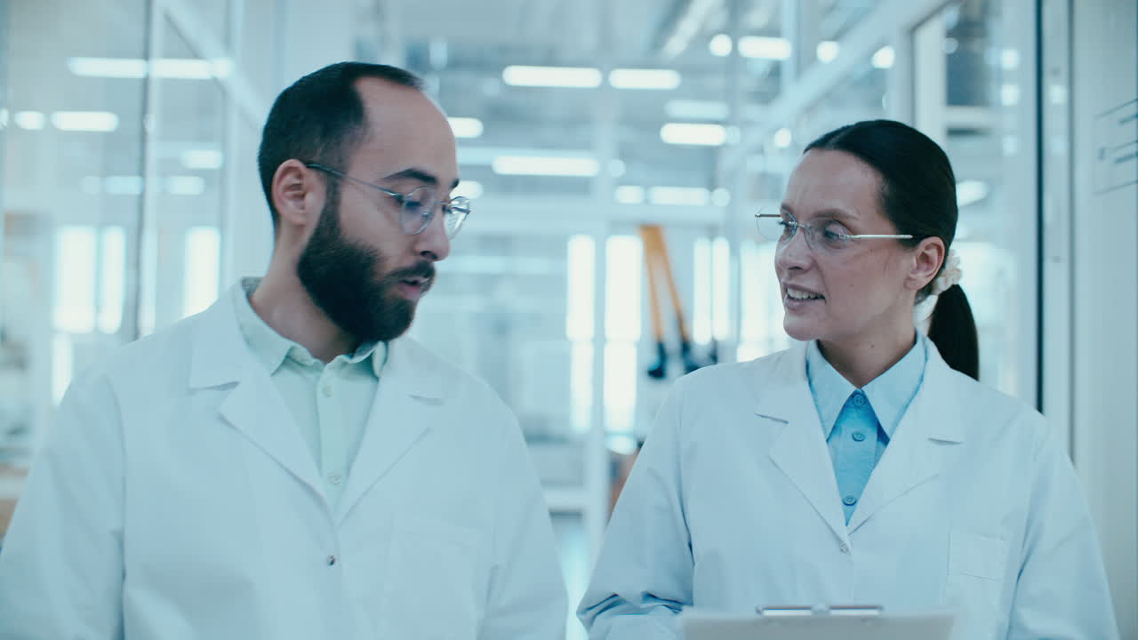 Two Scientists Discussing Research Data while Walking in Laboratory