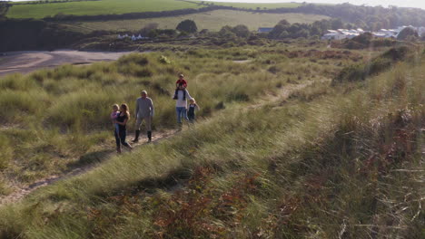 drone shot of multi-generation family on vacation walking through sand dunes on beach vacation