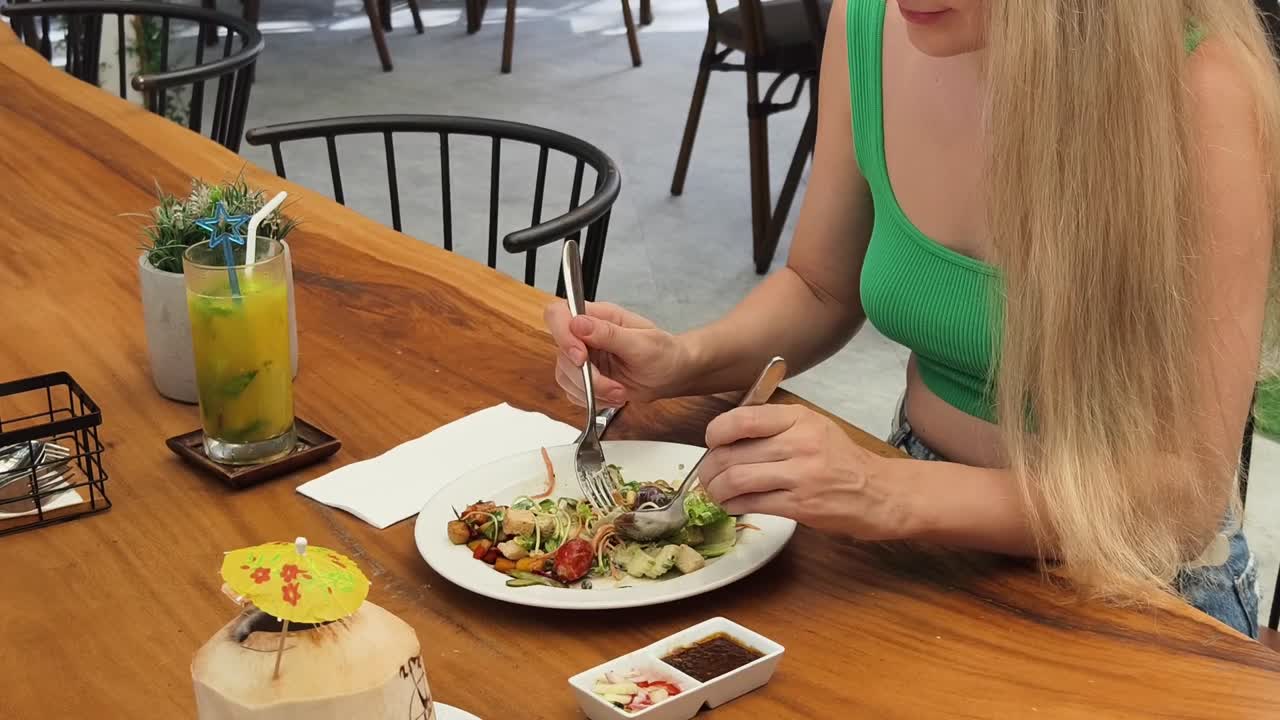 mujer comiendo una ensalada en un restaurante al aire libre