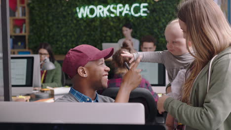 happy business woman mother holding baby playing with colleague discussing project in diverse modern office workplace