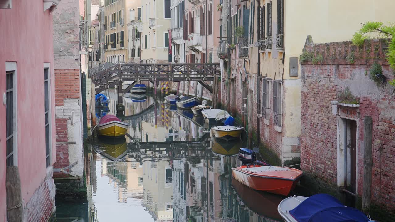 Calm water reflects canal boats and buildings in peaceful Venice district