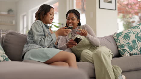 Two women using smartphones on a couch