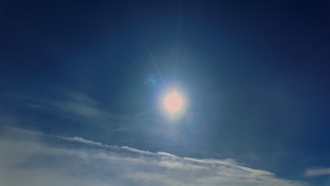 Aerial cockpit view flying in the upper atmosphere with the sun and its hallo of crytal ice particles in a deep blue sky