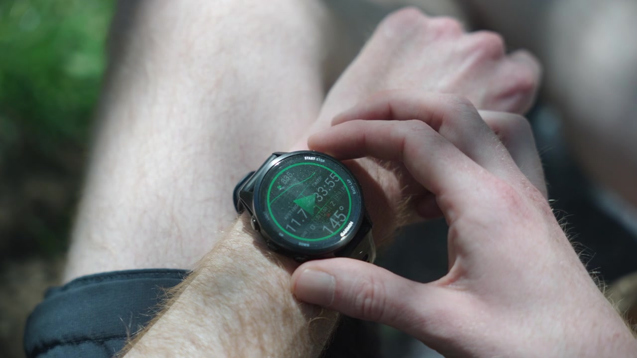 Close-up of a trekker setting up a digital sports smartwatch on their wrist. Checking fitness tracking, heart rate, and GPS navigation data during an active outdoor adventure