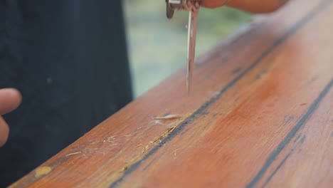 usando un cuchillo para cortar la madera dañada del tablón de la cabina del barco de madera