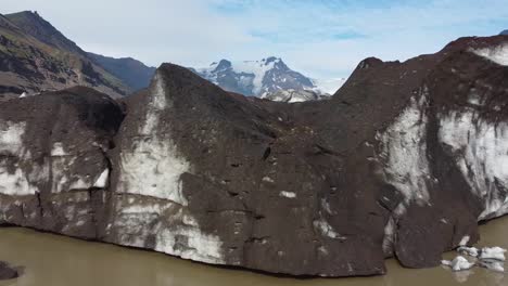 glacier covered in volcanic ashes in iceland, aerial opening shot