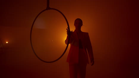 woman in a suit performing with an aerial hoop in a studio setting