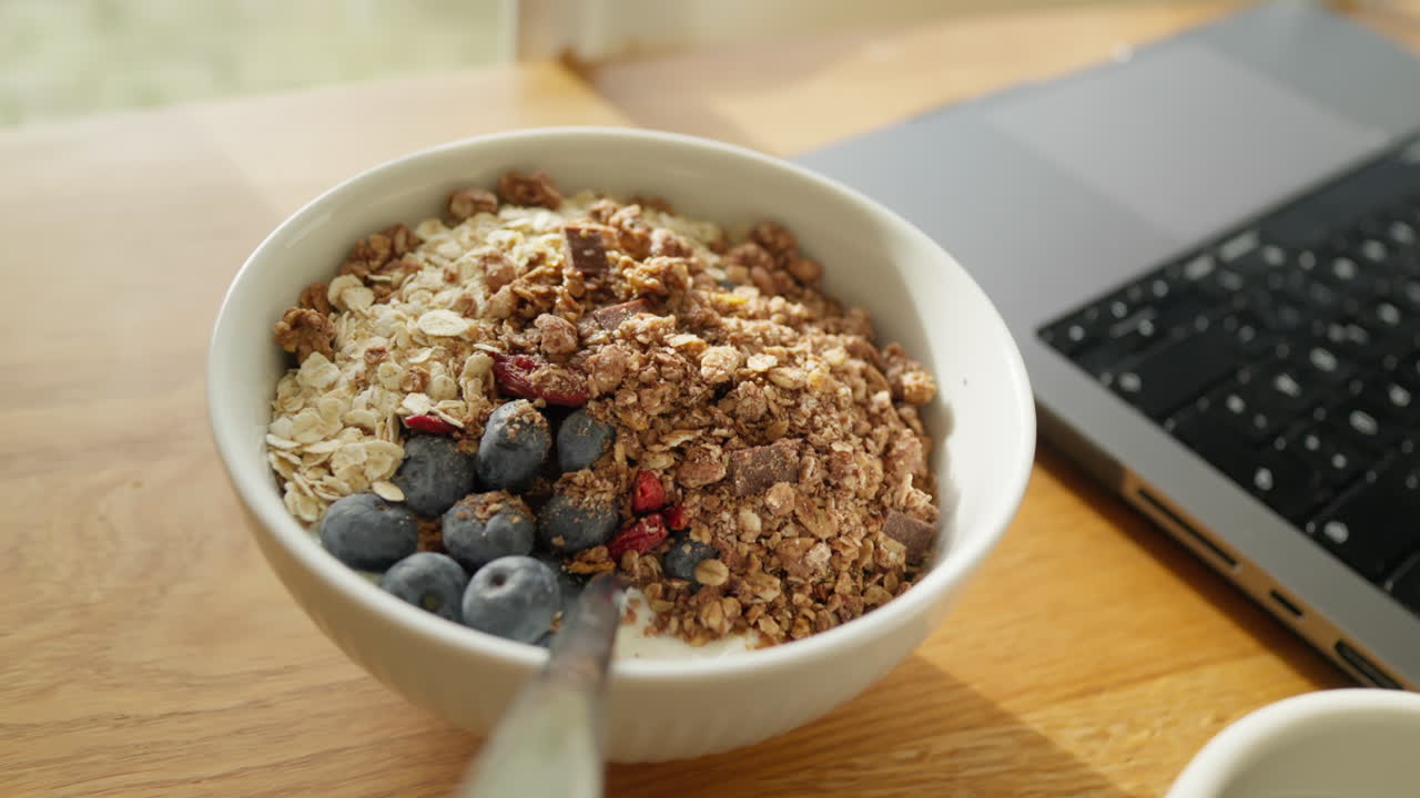una acogedora configuración de trabajo desde casa con un cuenco de desayuno de granola y café
