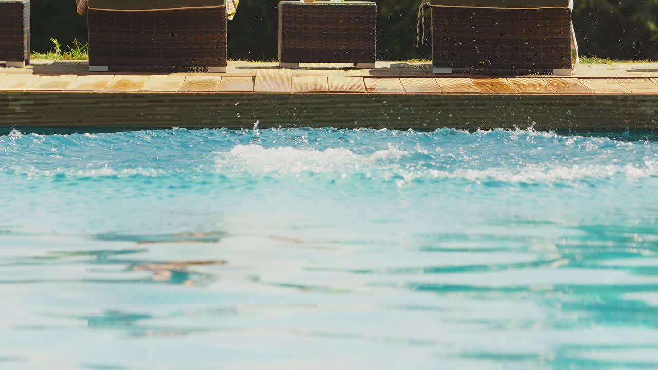 Par ved swimmingpool på sommerferie med mand der dykker ned i vandet