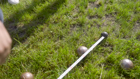 top view of a man calculating distance between petanque balls in the park