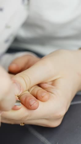 a detailed vertical view shows an adult gently clipping a child's fingernail, focusing on care, safety, and hygiene, capturing a nurturing moment between child and caregiver in soft lighting.