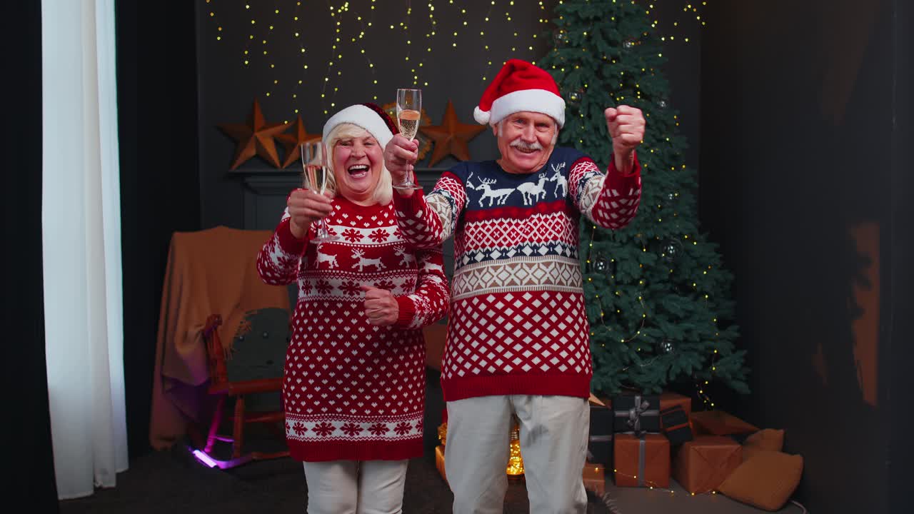 Happy senior family couple celebrating christmas at home clinking glasses and drinking champagne