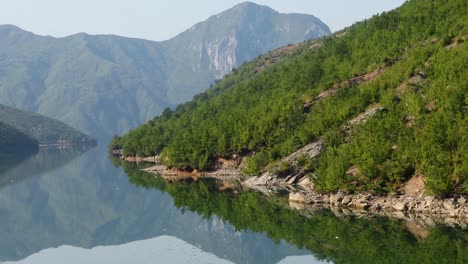 bergsee in albanien mit ruhigem wasser, das hohe gipfel und grüne vegetation widerspiegelt