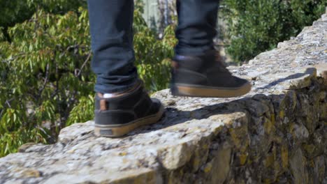 cerca de las piernas de un hombre caminando sobre una pared de piedra en un viejo pueblo en cámara lenta en francia