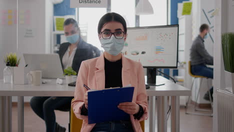 front view of businesswoman wearing face mask while talking on online video call meeting