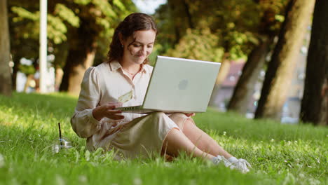 Woman-using-credit-bank-card-and-laptop,-transferring-money,-purchases-online-shopping-in-city-park