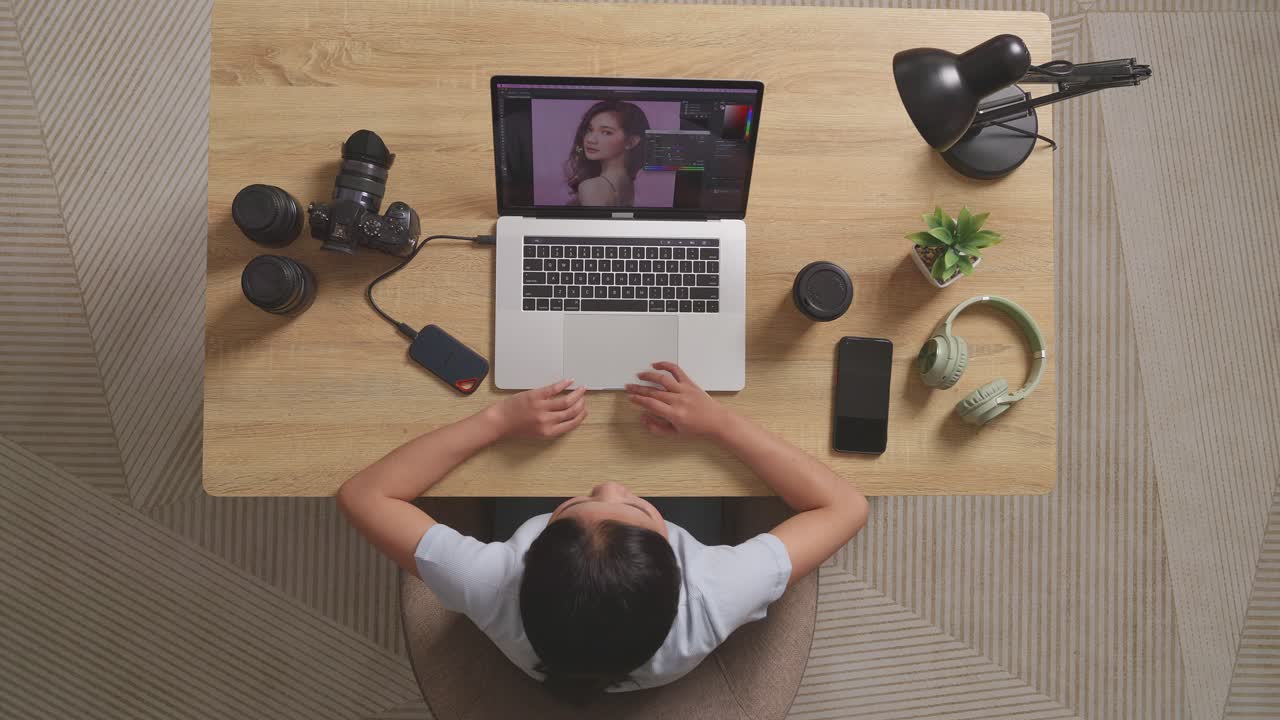 Top View Of A Woman Editor Shaking Her Head And Having A Headache While Sitting In The Workspace Using A Laptop Next To The Camera Editing Photo Of A Woman At Home