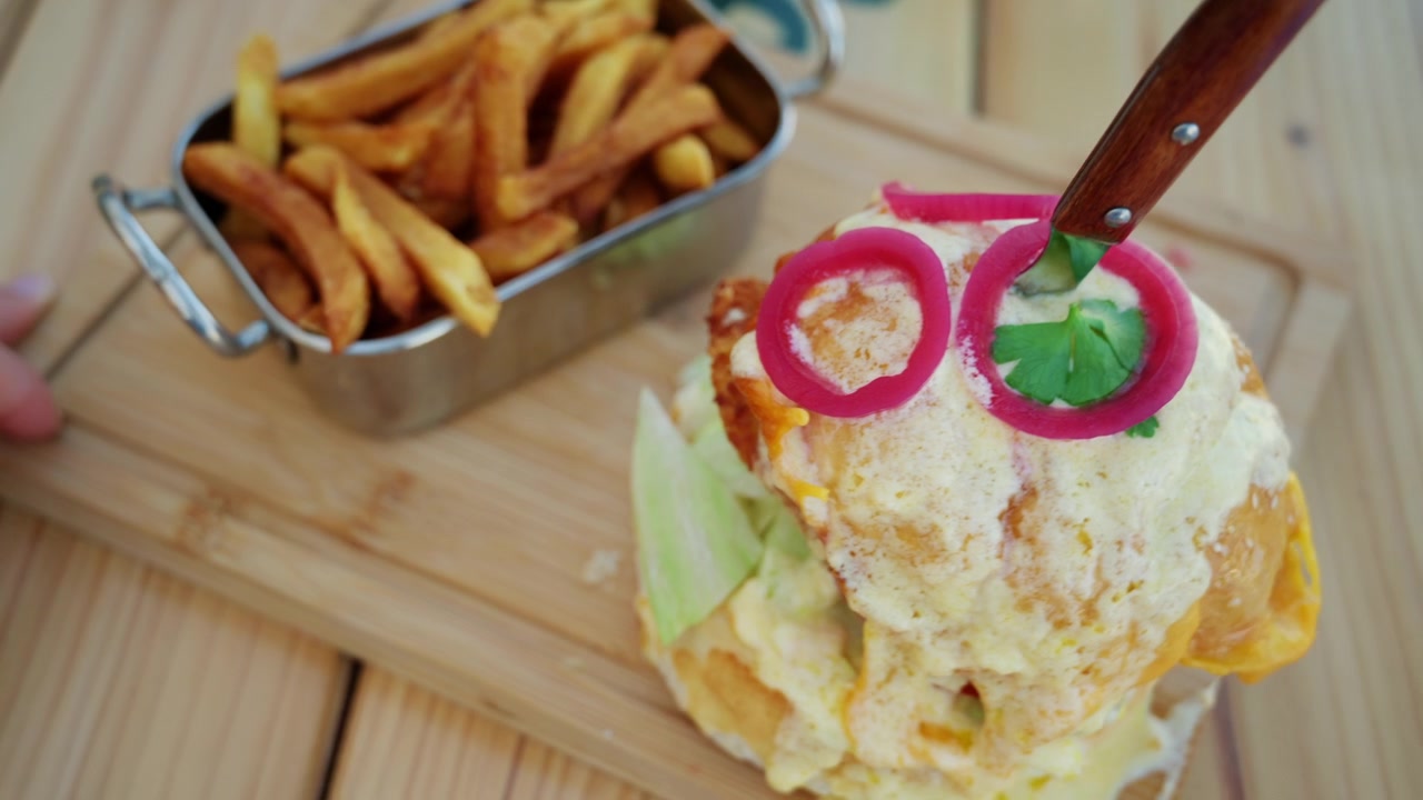Hambúrguer gourmet com queijo derretido e batatas fritas crocantes servido em restaurante à beira-mar