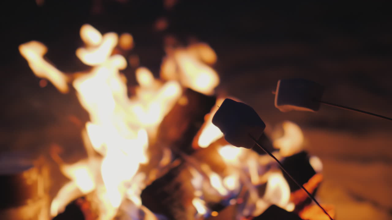 жарит зефир на костре крупным планом в кадре видны только палочки с зефиром