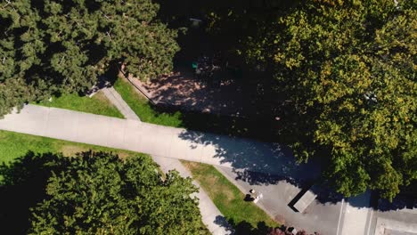 1-4 modern futuristic circlular shaped park birds eye view aerial rise over empty dry water fountain pool across restricted childrens park during covid-19 pandemic social distancing city bus hub paths