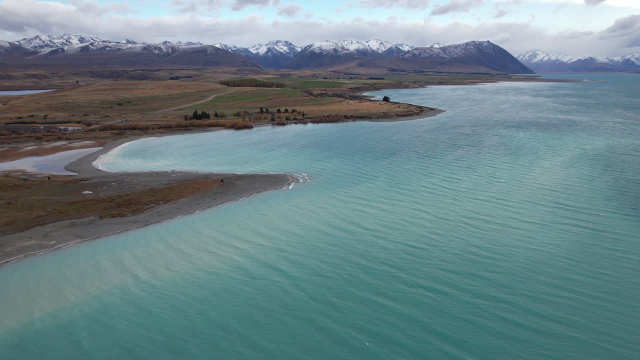 Turquoise Waters Of Lake Tekapo In New Zealand With Southern Alps In Background. wide aerial shot