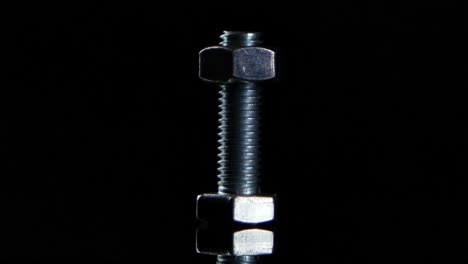 metal bolt and nuts on black background with reflection