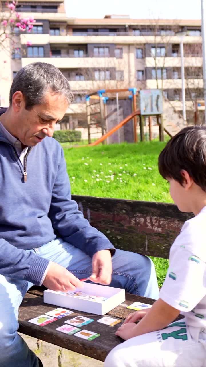 Man and Boy Playing Card Game Outdoors in Park