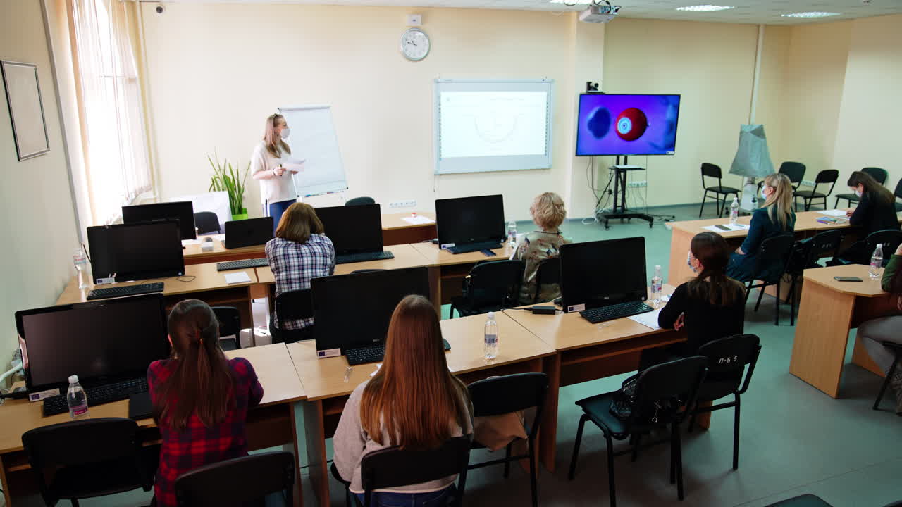 Medical university auditorium with lecture on ophthalmology in process. Students listen to a lecture and look at the screen with eyeball structure.
