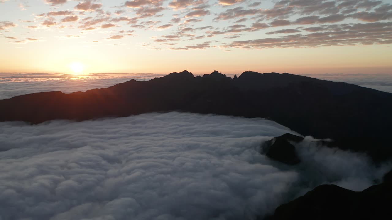 Alba idilliaca con nuvole basse e montagne che creano una scena paradisiaca, ripresa con drone