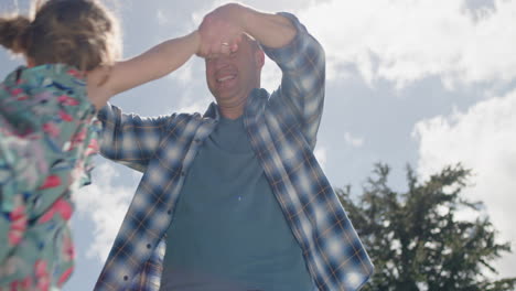 Glücklicher-Vater-Und-Tochter,-Die-Zusammen-Im-Garten-Im-Hinterhof-Spielen.-Glückliches-Kleines-Mädchen,-Das-Spaß-Mit-Papa-Hat,-Der-Sein-Kind-Spielerisch-Schwingt-Und-Die-Freiheit-Seiner-Kindheit-Im-Freien-Genießt,-4K