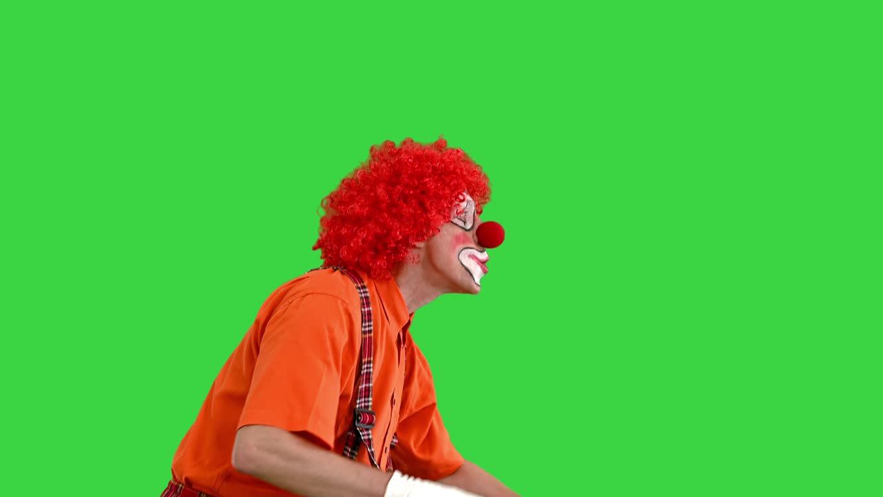 payaso merodeando y haciendo ser silencioso gesto a la cámara en una pantalla verde, llave de croma