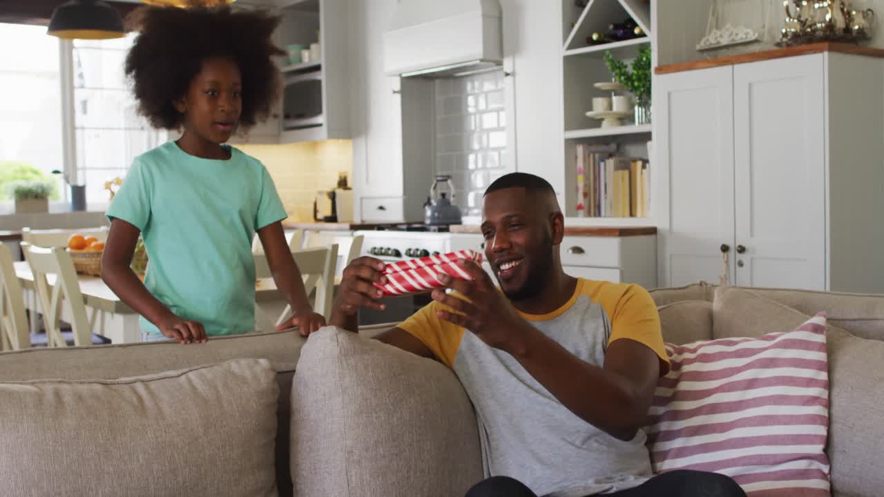 African american daughter giving her father a present in a gift box